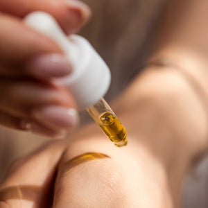 Dropper of Dew Drops Nourishing Face Oil going onto back of hand